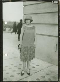 Frau in Kleid und Mantel auf dem Rennplatz