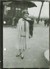 Frau in Kleid und Mantel auf dem Rennplatz
