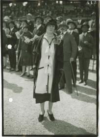 Frau in Kleid und Mantel auf dem Rennplatz in Longchamp