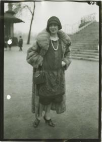 Frau in Kleid und Mantel auf dem Rennplatz