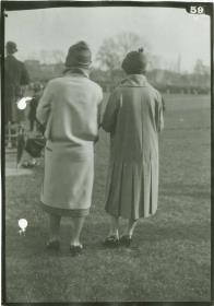 Frauen in Mänteln auf dem Rennplatz