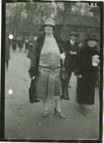 Frau in Kleid und Mantel auf dem Rennplatz