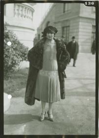 Frau in Kleid und Mantel auf dem Rennplatz