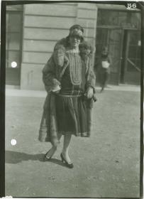 Frau in Kleid und Mantel auf dem Rennplatz