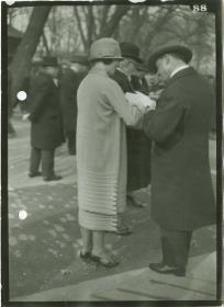 Frau und Männer in Mänteln auf dem Rennplatz
