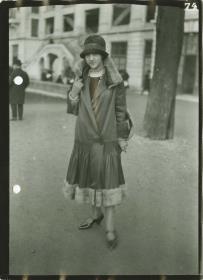 Frau in Kleid und Mantel auf dem Rennplatz