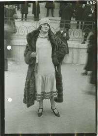 Frau in Kleid und Mantel auf dem Rennplatz