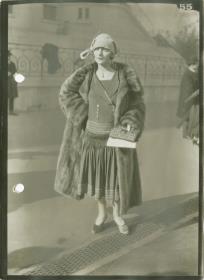 Frau in Kleid und Mantel auf dem Rennplatz