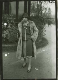 Frau in Kleid und Mantel auf dem Rennplatz
