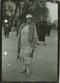 Frau in Kleid und Mantel auf dem Rennplatz