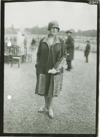Frau in Kleid und Mantel auf dem Rennplatz in Longchamp