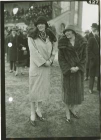 Frauen in Mänteln auf dem Rennplatz