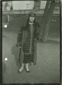 Frau in Kleid und Mantel auf dem Rennplatz