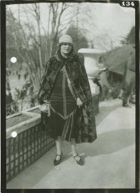 Frau in Kleid und Cape auf dem Rennplatz