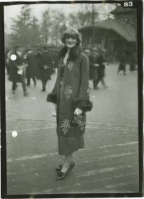 Frau in Kleid und Mantel auf dem Rennplatz