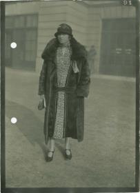 Frau in Kleid und Mantel auf dem Rennplatz