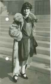 Frau in Kleid und Mantel auf dem Rennplatz