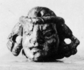 Tragische Maske, in den steif herabhängenden Locken und oben im Kopf durchbohrt
