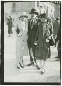 Frauen in Kostümen und Mann in Anzug auf dem Rennplatz in Longchamp