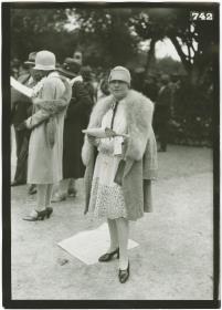 Frau in Kleid und Mantel auf dem Rennplatz in Deauville