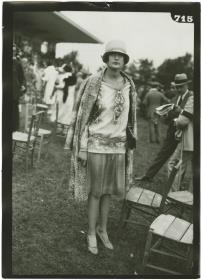 Frau in Kleid und Mantel auf dem Rennplatz in Deauville