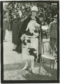 Frau in Kleid und Mantel auf dem Rennplatz in Deauville