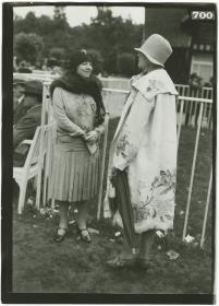 Frau in Kleid und Frau in Mantel auf dem Rennplatz in Deauville