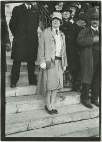 Frau in Kostüm und Mantel auf dem Rennplatz in Auteuil