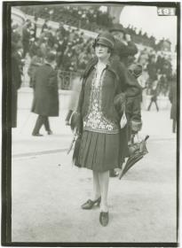 Frau in Kleid und Mantel auf dem Rennplatz in Auteuil