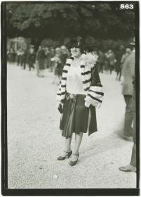Frau in Kleid und Mantel auf dem Rennplatz in Longchamp