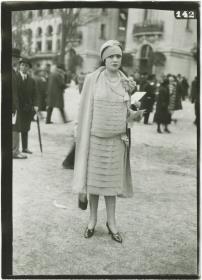 Frau in Kleid und Mantel auf dem Rennplatz in Longchamp